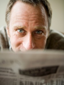 Happy man distracted when reading a newspaper.